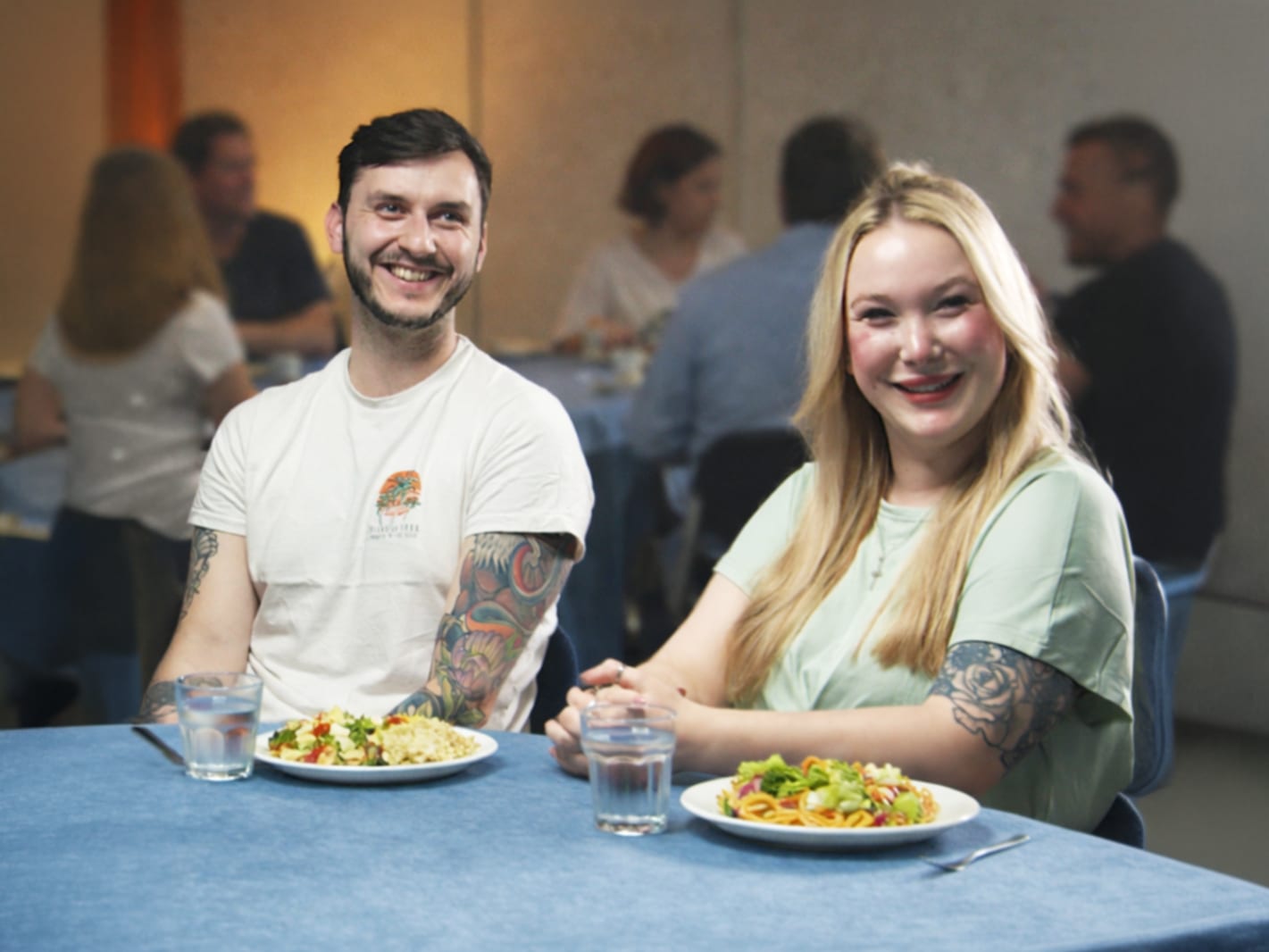 A couple smiling over a shared meal at Explore!