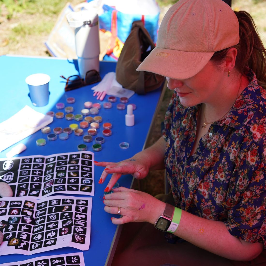 A Hope volunteer face painting and doing glitter tattoos at a community event