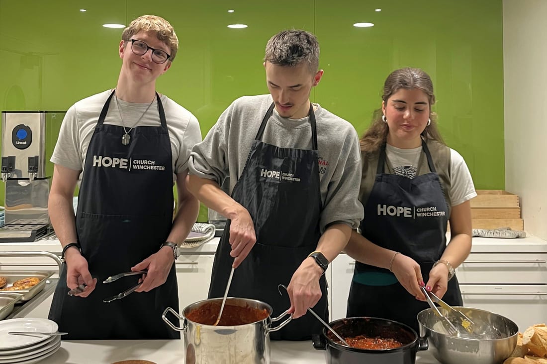 Students cooking a meal together in Hope Church aprons