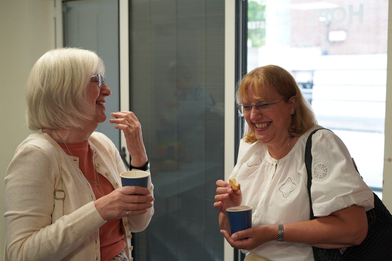 Two women chatting over coffee after a service